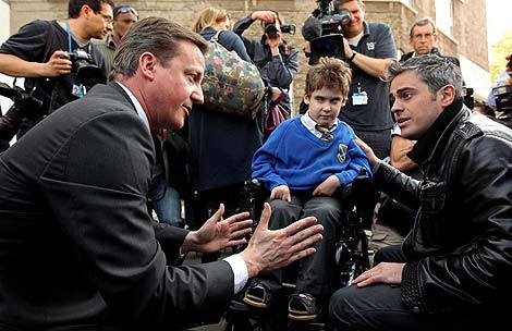 David Cameron habla con el padre de un niño discapacitado. | Afp